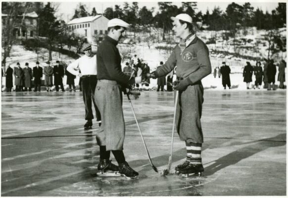 Två hockeyspelare skakar hand på isen.