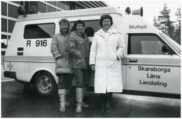 Tre kvinnor framför Ambulans.