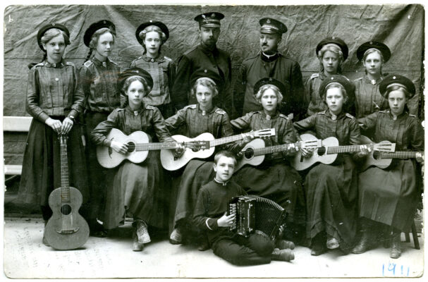 Grupp med 10 kvinnor och två män, de sittande har gitarrer. 