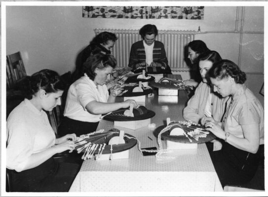 Kvinnor vid ett bord övar knyppling.