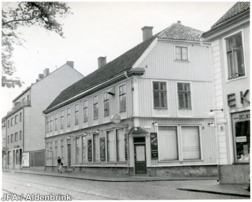 Ljus träbyggnad med ensam person utanför.