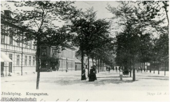 Välklädda kvinnor och andra personer i en allé.