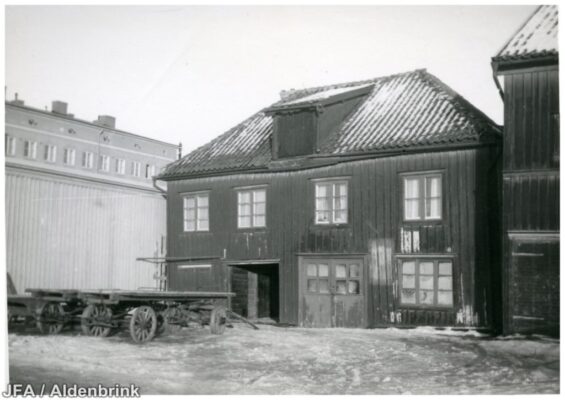 Vagnar utanför en träbyggnad i dåligt skick.