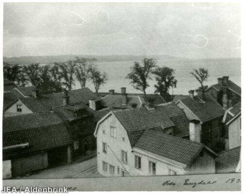 Några trähus och Vättern sedda ovanifrån. 