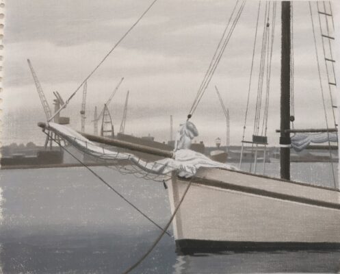 Fören av en vit segelbåt, hamn i bakgrunden.