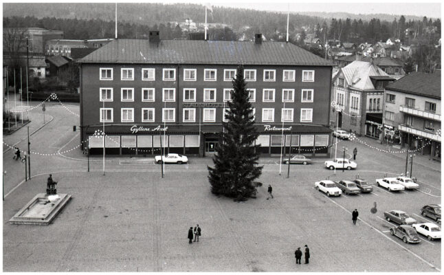 Människor, bilar och cyklar i julpyntad stadsmiljö.