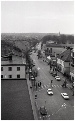 Människor, bilar och cyklar i julpyntad stadsmiljö.