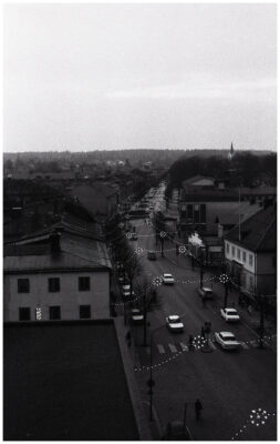 Människor, bilar och cyklar i julpyntad stadsmiljö.