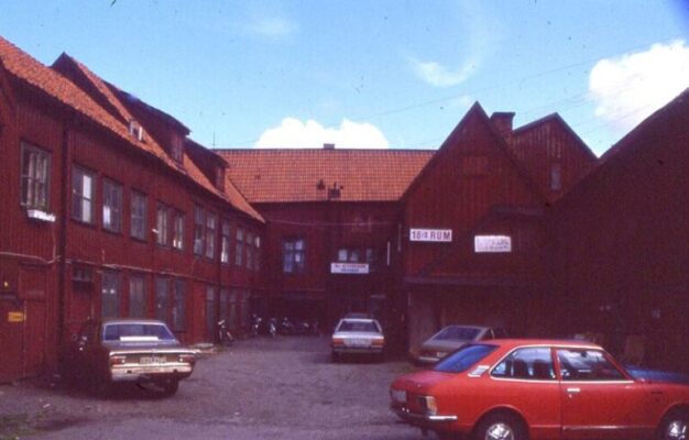 Parkering mellan röda trähus. 