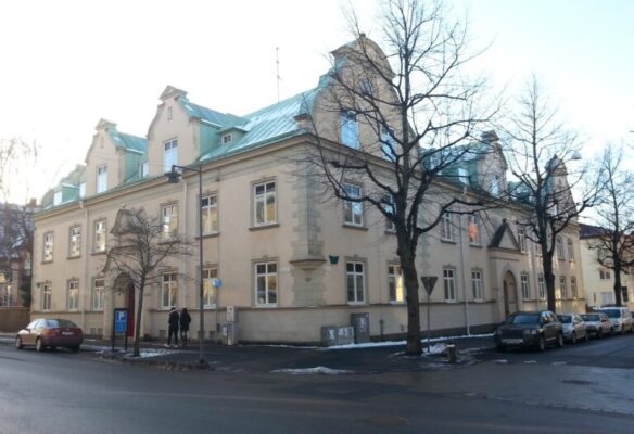 Stenhuset med dess blågröna tak och ett antal bilar parkerade nedanför.