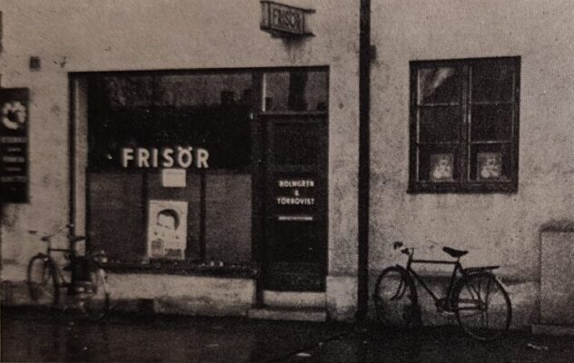 Stenbyggnad med frisersalong och två cyklar.
