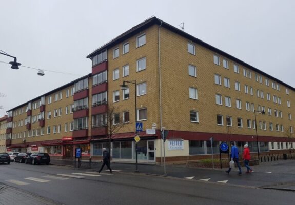 Gul tegelbyggnad med röda accenter belägen vid en korsning.