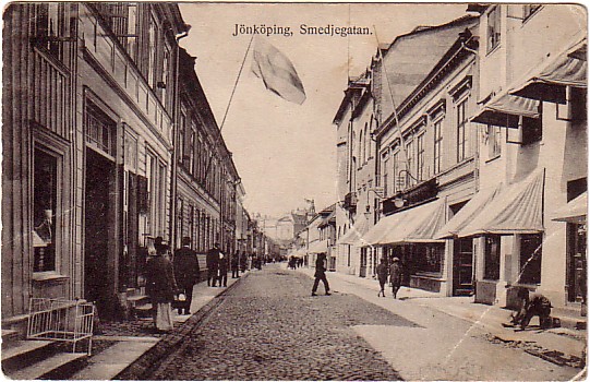 Stengata med många människor, butiker på båda sidor med markiser på högersidan.