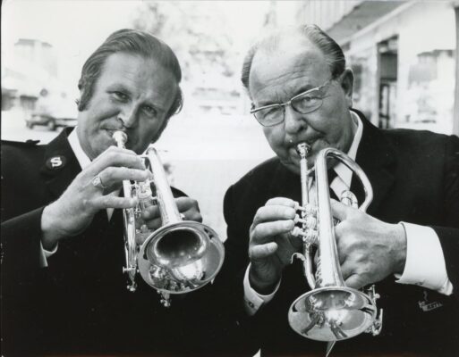 Två män blåser trumpet.