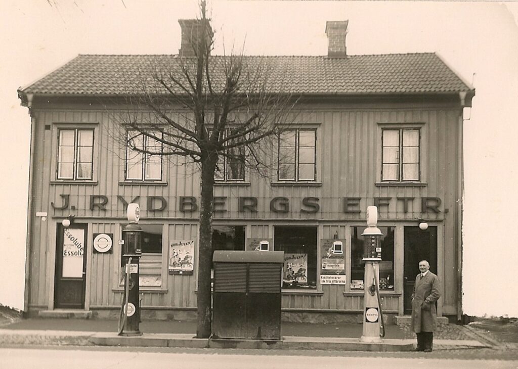 Man vid en bensinpump utanför hus med texten "J Rydbergs Eftr".