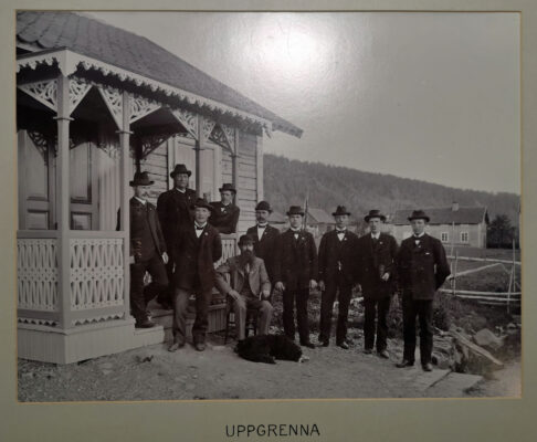 Tio män i kostym vid en farstukvist.