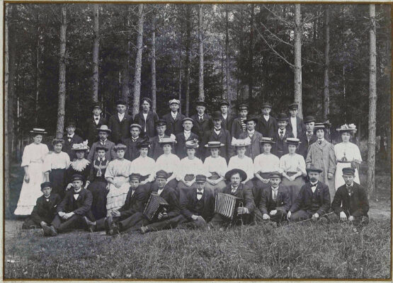 Runt fyrtio personer, både män och kvinnor, uppställda i skogen för fotografering.