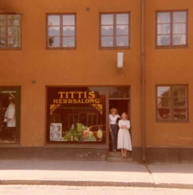 Orange byggnad med frisersalong, två kvinnor i entrén.