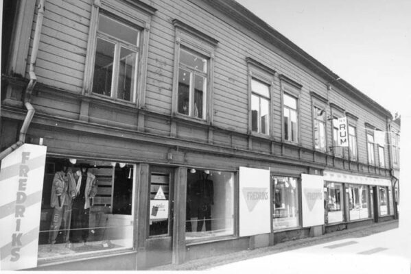 Stengata kantat av trähus, butik med klädda skyltdockor.