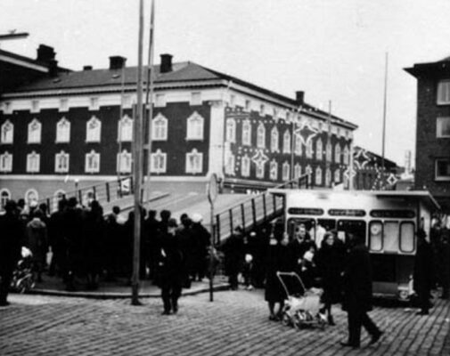 Många personer vid broöppning, kiosk till höger vid kanalen.