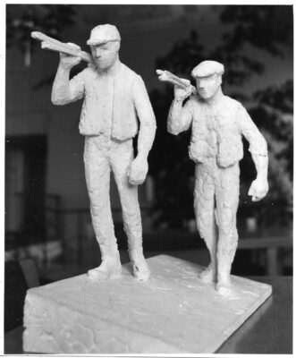 Skulptur av två män som bär stänger över sina axlar. 