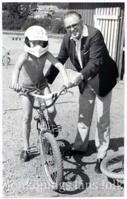 Man stöder en pojke på cykel. 