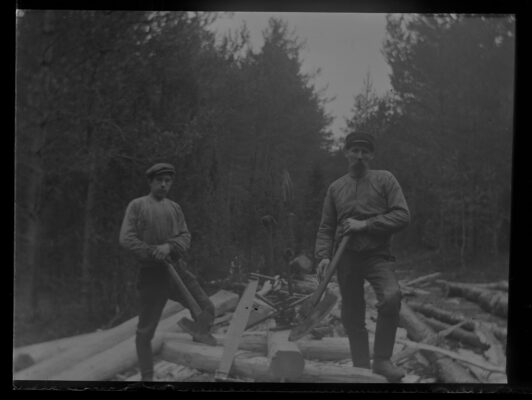 Två unga skogsarbetare med virke.