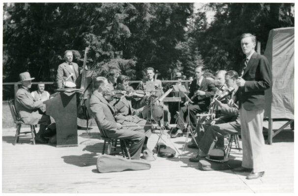 Orkester på ca tio personer utomhus på en träparkett.