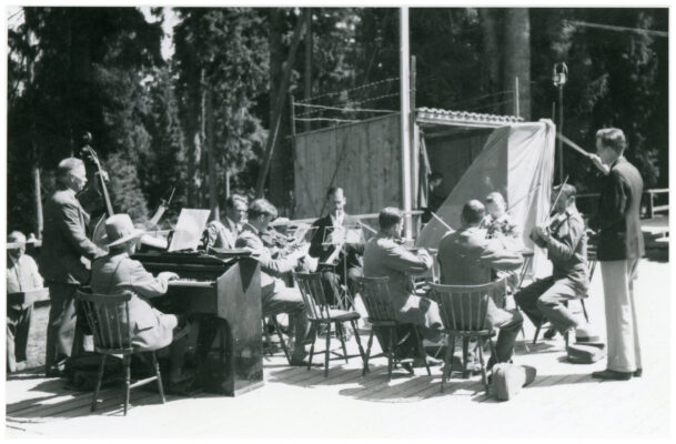 Orkester på ca tio personer utomhus på en träparkett.
