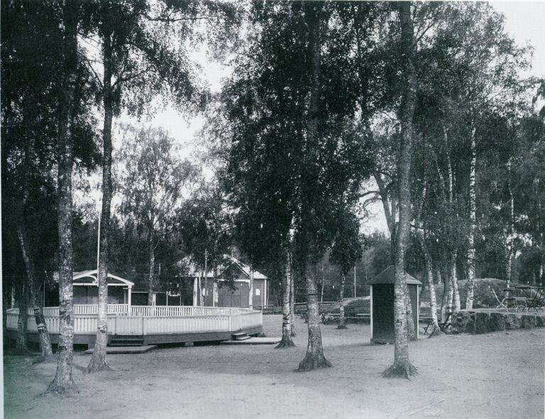 Några byggnader, en potentiell dansbana, några picknickbord och träd.