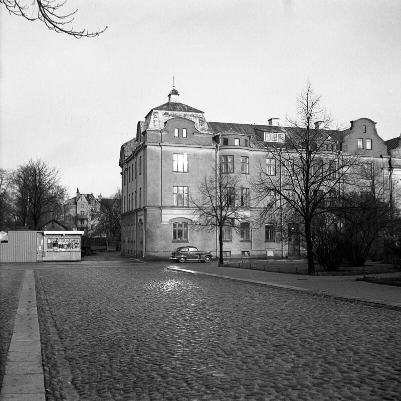stenbelagd gata utanför stort stenhus. 