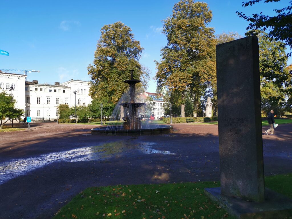 Rådhusparken i skugga med rest sten och fontän.