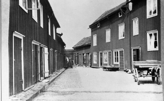 Gata kantad av trähus med parkerad vagnar.