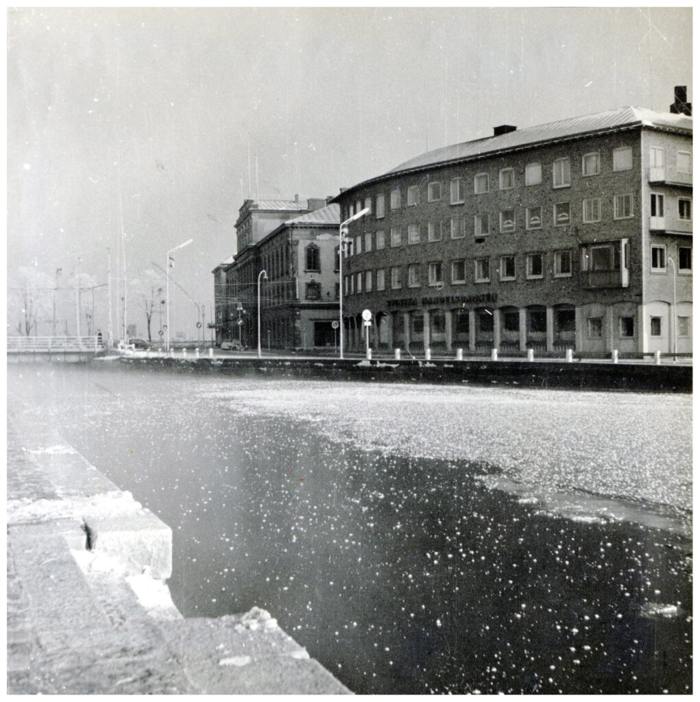 Istäckt kanal kantad av byggnader.