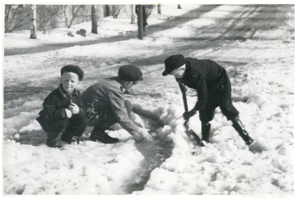 Tre pojkar leker i snön.