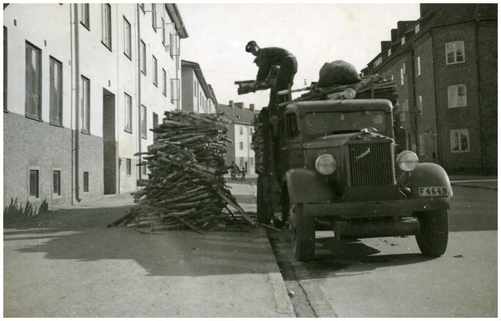 Man lastar ved från en bil ner på gatan.