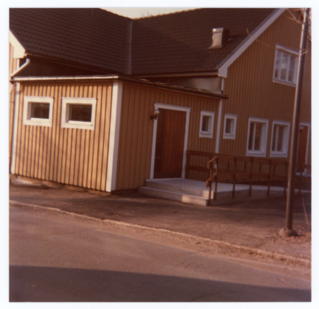 Knuten och entrén på ett gult trähus.