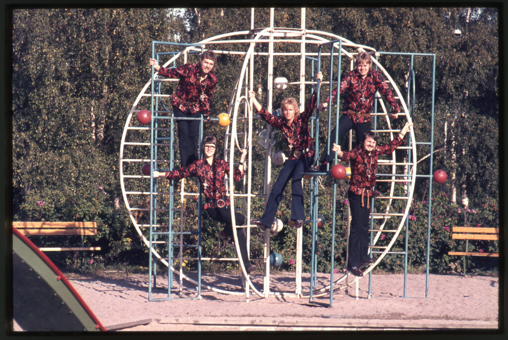 Band med rödsvarta kläder poserar i en lekställning.