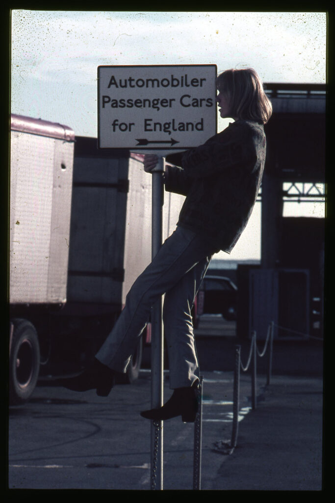 En ung man håller sig i en skylt med vägvisning för bilar som ska ombord färjan till _England. 