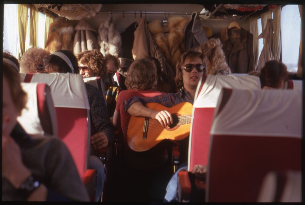 Insidan av turnébuss med flera människor varav en med gitarr.