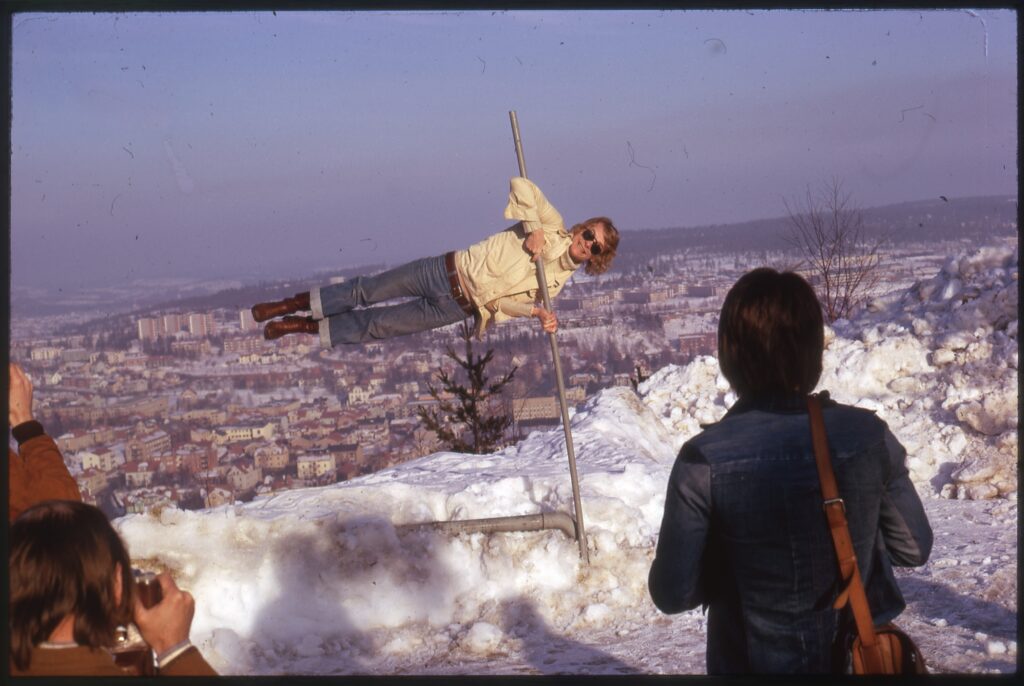 Man håller sig horisontellt över marken i en metallpåle en snöig dag.