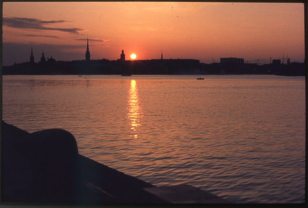 Silhuett av Stockholm över vattnet vid solnedgången.