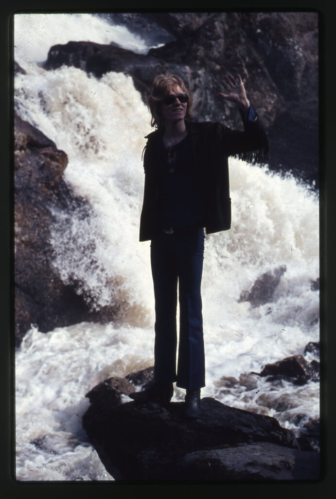 Ung man på en sten i strömmen.