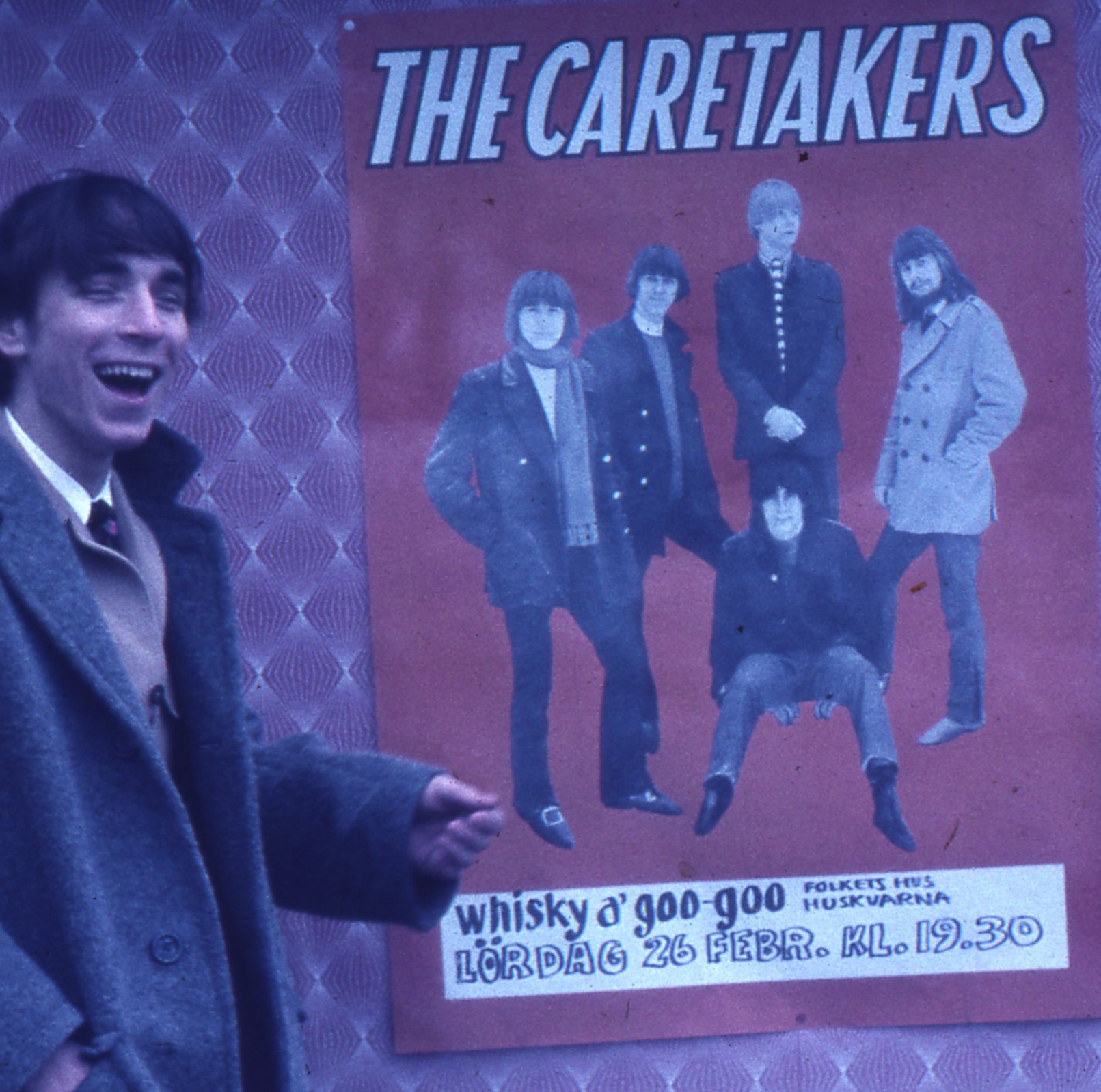 Glad man pekar på affisch med Caretakers.