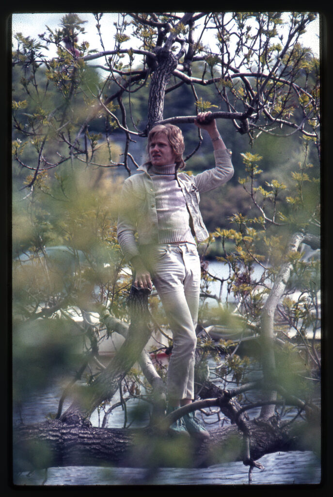 Man poserar på horisontell trädstam.